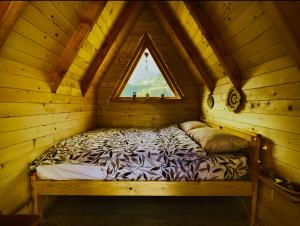 een bed in een houten hut met een raam bij Kapetanovo Jezero Bungalov in Podgorica