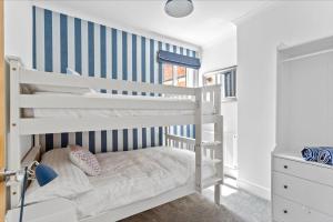 a white bunk bed in a bedroom with a striped wall at Captain's Quarters in Hythe