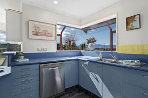 eine blaue Küche mit einem Waschbecken und einem Fenster in der Unterkunft Mountain Majesty on Orchard-Wanaka Holiday Home in Wanaka