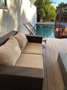 a wicker couch sitting on a deck next to a pool at Orient Bay villa in Saint Martin