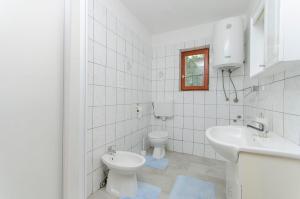 a white bathroom with a toilet and a sink at Apartments Seafront Jadranka in Stara Novalja