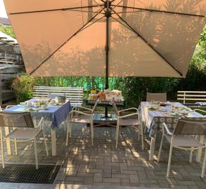 een patio met tafels en stoelen en een parasol bij B&B La Salina in Cannuzzo