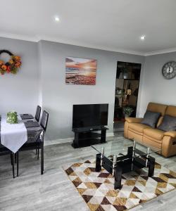 FM Homes & Apartments 3 Bedroom Motherwell في ماذرويل: غرفة معيشة مع أريكة وطاولة