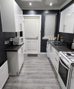 cocina con armarios blancos y puerta blanca en FM Homes & Apartments 3 Bedroom Motherwell, en Motherwell