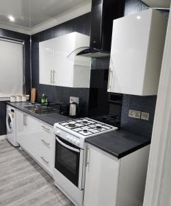 FM Homes & Apartments 3 Bedroom Motherwell في ماذرويل: مطبخ بدولاب بيضاء وفرن علوي موقد