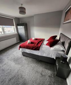 FM Homes & Apartments 3 Bedroom Motherwell في ماذرويل: غرفة نوم بسرير ومخدات حمراء