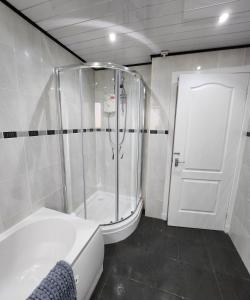 a bathroom with a shower and a white tub at FM Homes & Apartments 3 Bedroom Motherwell in Motherwell