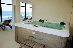 uma banheira de hidromassagem num quarto com o oceano em Japandi Queen Std - Infinity Pool & Spa Resort em Mamaia Nord – Năvodari