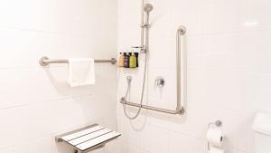 a bathroom with a shower with white tiles at Holiday Inn Auckland Airport by IHG in Auckland