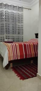 Cama en habitación con manta roja y blanca en Dar Malaika, en Oualidia