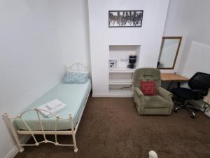 羅奇代爾的住宿－Spacious Flat Near Rochdale Centre Self Check-in Free Parking & Fast Wi-Fi，一间卧室配有一张床、一把椅子和一张书桌