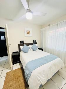 a bedroom with a large white bed with blue pillows at Illovo Beach View Apartment at Illovo Views in Kingsburgh