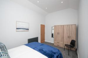 1 dormitorio con 1 cama y 1 silla en Historical Holmehill Lodge, en Dunblane