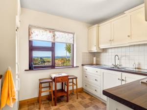 een keuken met witte kasten en een tafel en een raam bij Flaherty Cottage in Ballyconneely