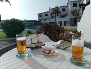 dos vasos de cerveza y un tazón de comida en una mesa en Casa Lago Azul 49 en Los Cancajos