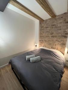 Bett in einem Zimmer mit einer Steinmauer in der Unterkunft La Vitrine in Gertwiller