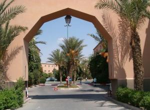 un arco que conduce a una calle con palmeras en Riad canne à sucre, en Marrakech