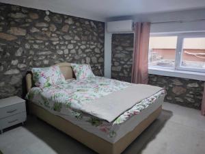 1 dormitorio con 1 cama con pared de piedra en Apartments Janiki, en Kruševo