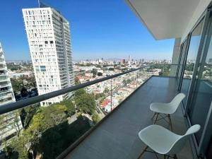 a balcony with two chairs and a view of a city at Park Life Guadalajara in Guadalajara