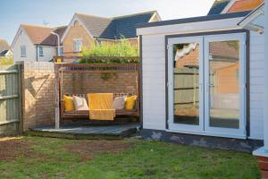 a white shed with a bench on a deck at The Opulent House Kent in Sheerness