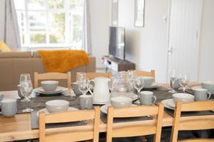 una mesa de comedor con platos y vasos. en The Opulent House Kent, en Sheerness