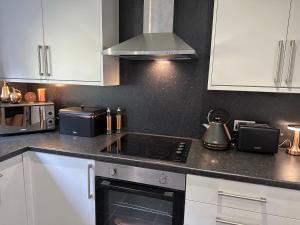 a kitchen with white cabinets and a stove top oven at Ty Cwm - Cwmcarn Valley House in Cwmcarn