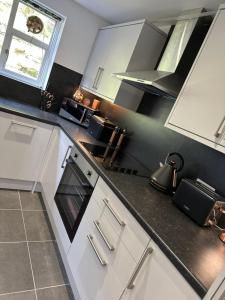 a kitchen with white cabinets and a black counter top at Ty Cwm - Cwmcarn Valley House in Cwmcarn