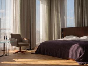 a bedroom with a bed and a chair and a window at Grand Hotel in Łódź
