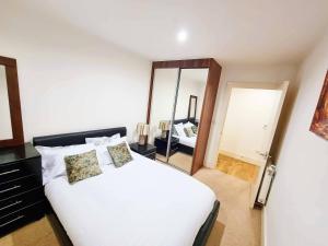 1 dormitorio con 1 cama blanca grande y espejo en Your Riverside Home 2 with Private balcony, en Woolwich
