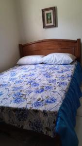 a bed with a blue and white comforter on it at Casa de temporada Lar Doce Mar de Itauna in Saquarema