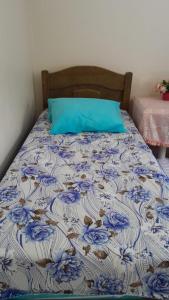 a bed with a blue and white comforter with a blue pillow at Casa de temporada Lar Doce Mar de Itauna in Saquarema