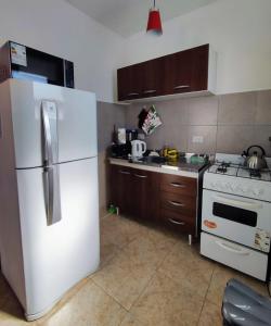 a kitchen with a white refrigerator and a stove at Luna Alojamiento Temporario in Puerto Madryn