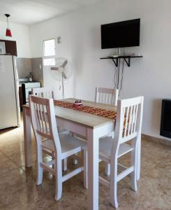 a dining room table with four chairs and a television at Luna Alojamiento Temporario in Puerto Madryn
