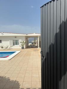 une clôture en face d'une maison avec piscine dans l'établissement Beachfront Villa and pool, à Puerto de Santiago