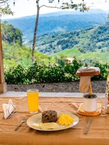 un tavolo con un piatto di cibo e un bicchiere di succo d'arancia di Cabañas Don Tito a Pejibaye