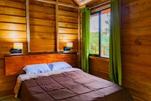 1 dormitorio con 1 cama con cortinas verdes y ventana en Cabañas Don Tito en Pejibaye