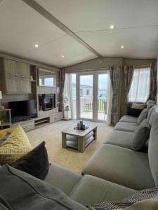 uma grande sala de estar com um sofá e uma mesa em The Fairways Hideaway - Northumberland em Newbiggin-by-the-Sea