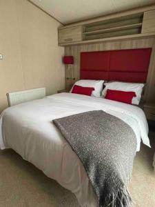 a bedroom with a large white bed with a red headboard at The Fairways Hideaway - Northumberland in Newbiggin-by-the-Sea