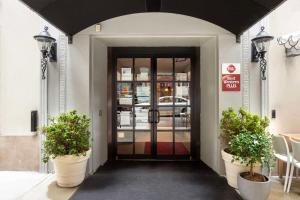 eine Tür zu einem Gebäude mit zwei Topfpflanzen davor in der Unterkunft Best Western Plus Hospitality House Suites in New York