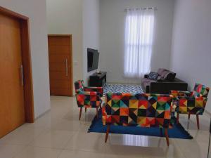 a living room with colorful chairs and a television at Casa de Temporada Maju - Olímpia - SP in Olímpia