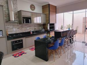 a kitchen with a bar with blue chairs in it at Casa de Temporada Maju - Olímpia - SP in Olímpia