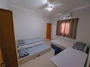 a small room with two beds and a table at Casa de Temporada Maju - Olímpia - SP in Olímpia +19 photos