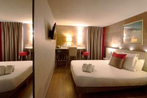 a hotel room with two beds and a table at Best Western l'Atelier 117 in Maubeuge