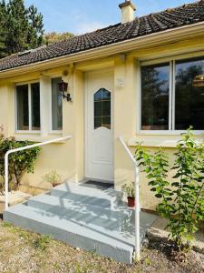 Cette petite maison dispose d'une porte blanche et d'une terrasse couverte. dans l'établissement Maison Bobochic parking et jardin by Art de Voyager, à Étretat