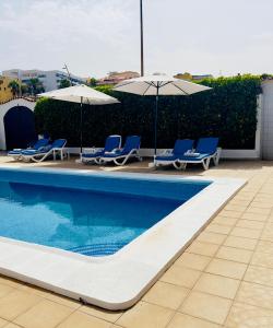 - une piscine avec des chaises et des parasols bleus dans l'établissement Beachfront Villa and pool, à Puerto de Santiago