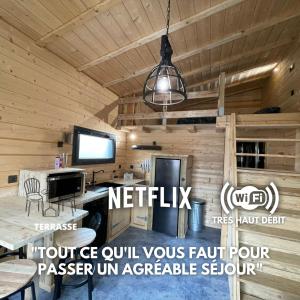 eine Blockhütte mit einem Tisch, einem TV und einer Hängeleuchte in der Unterkunft Cab-Appart Mont de Marsan in Mont-de-Marsan