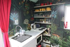 a kitchen with a sink and a red curtain at The Writer's Studio (stylish garden guesthouse)  +47 photos