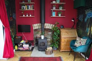 a living room with a fireplace and a red wall at The Writer's Studio (stylish garden guesthouse) 