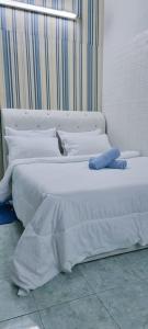 ein weißes Bett mit einem blauen Kissen darüber in der Unterkunft My Homestay Tronoh Seri Iskandar in Teronoh