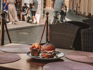 a plate of food on a table with a sandwich and fries at Flamingo Rezidencia Apartman in Eger +26 photos